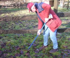 A man pushing a broomstick handle into the ground near molehills.