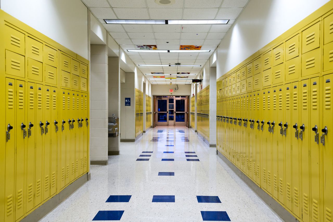 A school hallway with yellow lockers lining each wall.