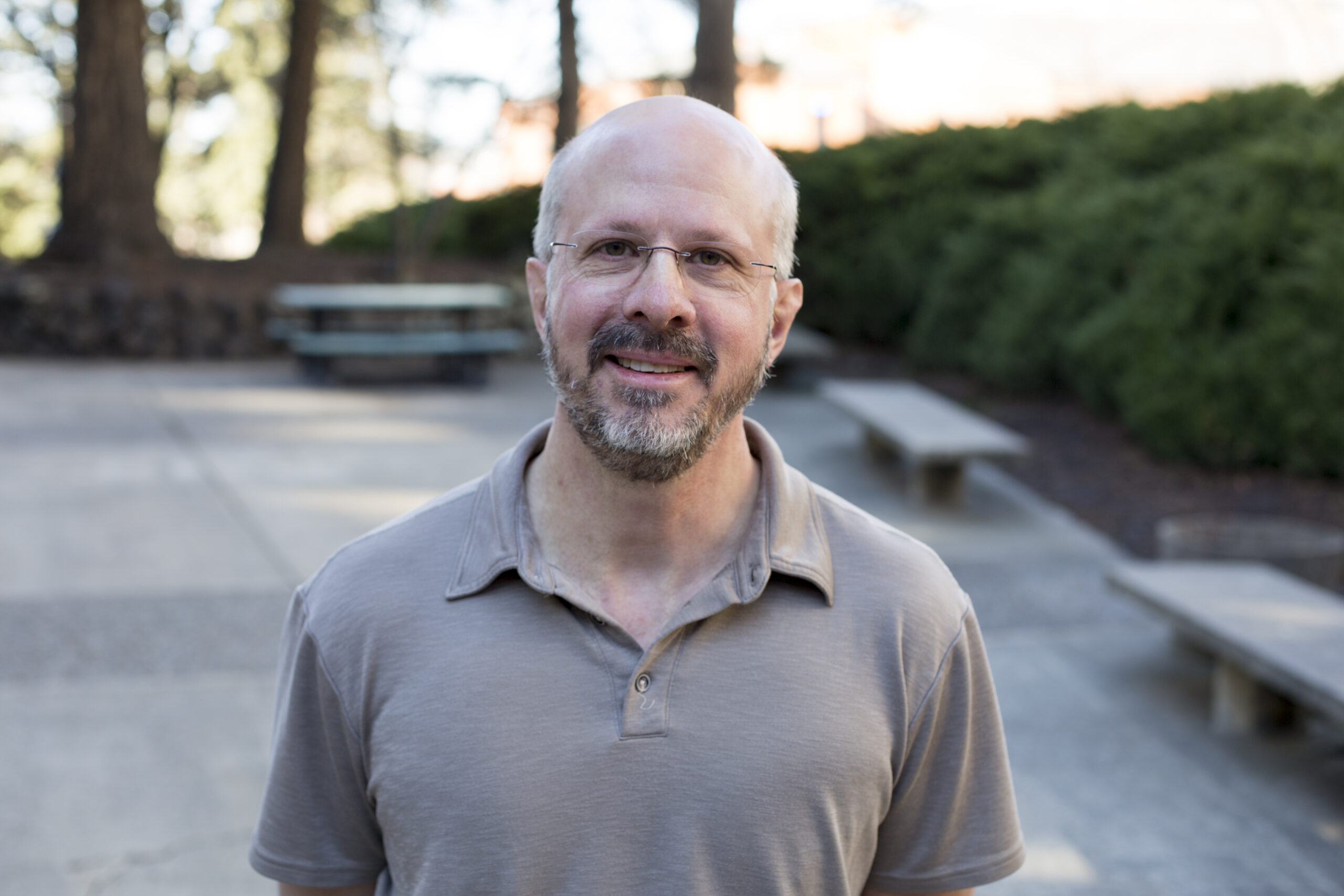 An image of Bruce Austin standing outside, smiling and wearing a light gray shirt.