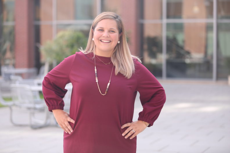 Lauren Bruno standing in front of the Education Addition, hands on hips.