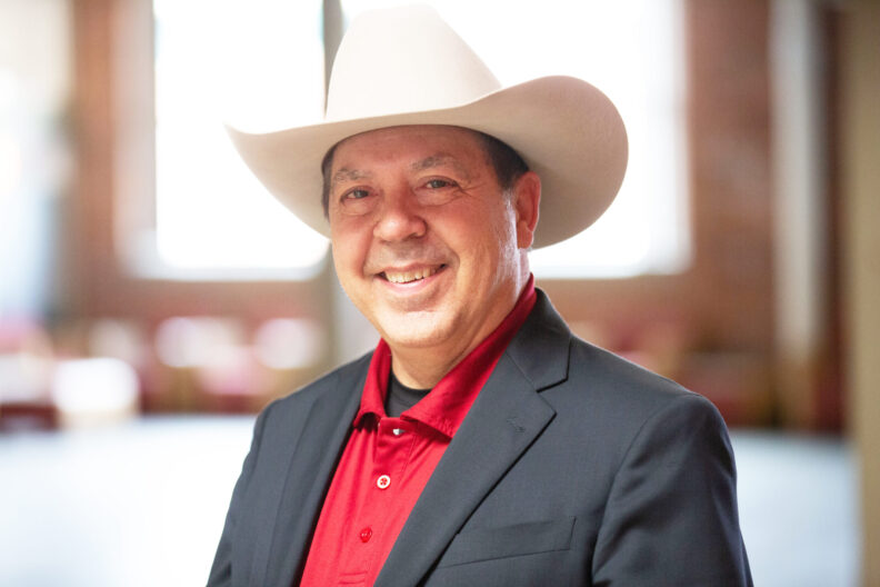 WSU faculty Richard McBride smiling at camera, cowboy hat positioned perfectly on his head.