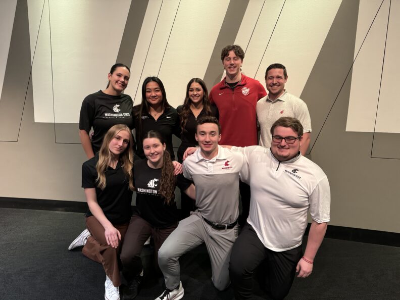 Photo of Lukas Krumpl with Strength and Conditioning students, all smiling at camera.