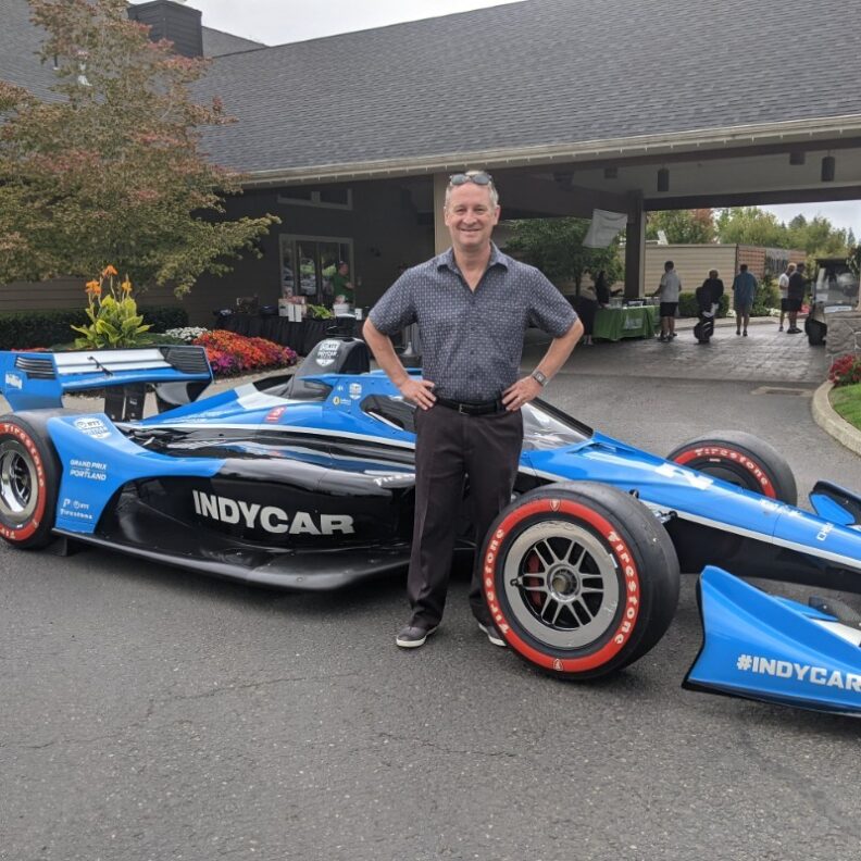 Giles Dowden smilling in front of an Indy car.