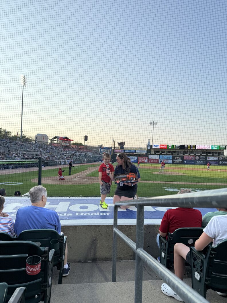 From the top of the dugout in between innings, Kinsey interviews a young fan.