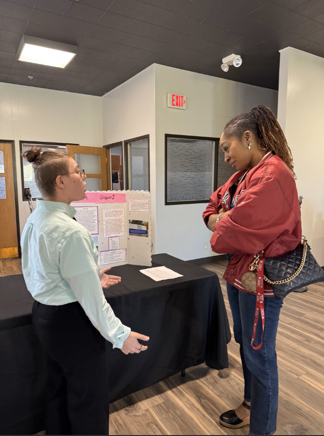 ROAR Student Kam Rogers presenting poster at Reverse Career Fair to Dean Karen Thomas-Brown.
