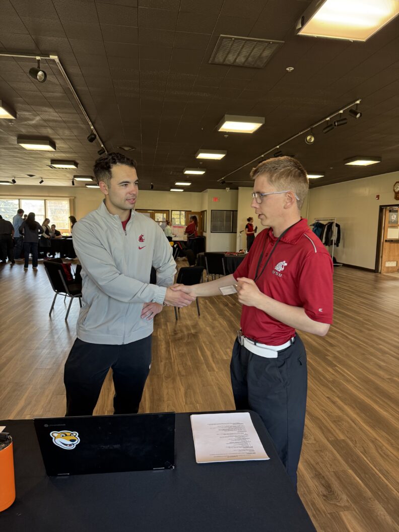 ROAR Student Xander Piatt presenting poster at Reverse Career Fair to Matt Lenti, the assistant safeties coach for WSU Football.