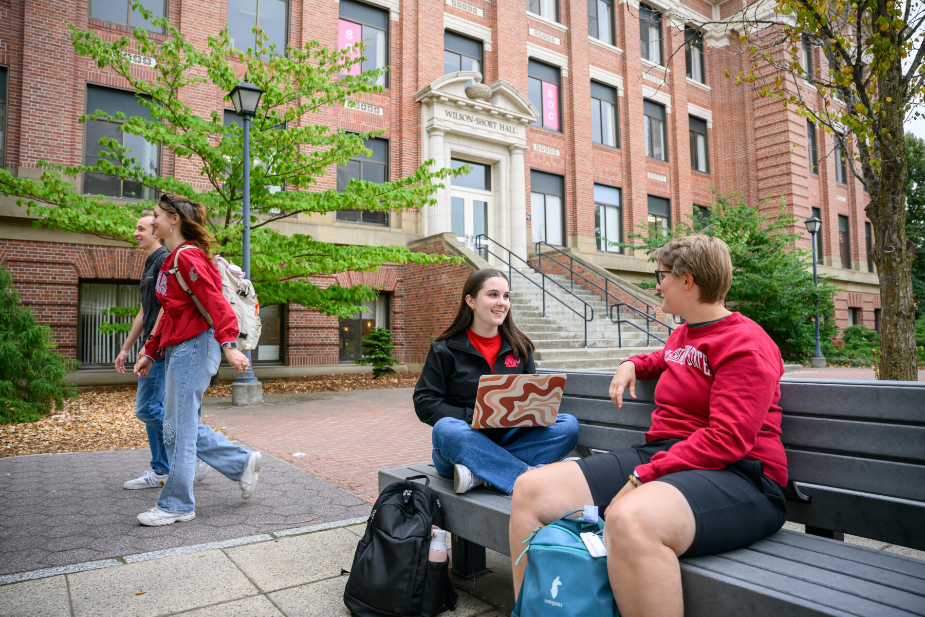 Students sitting on a bench talking talking