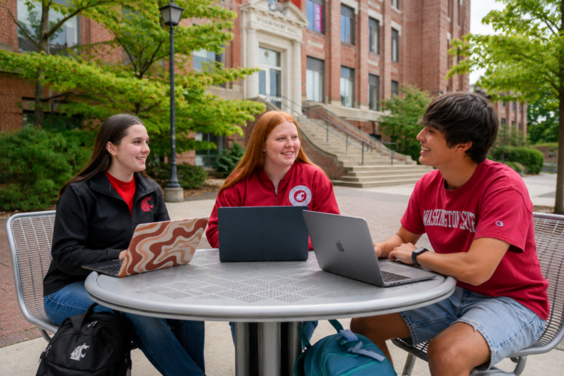 three students sitting outside chatting
