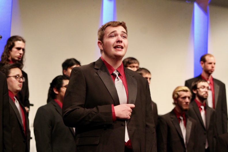 A photo of a man singing with a choir
