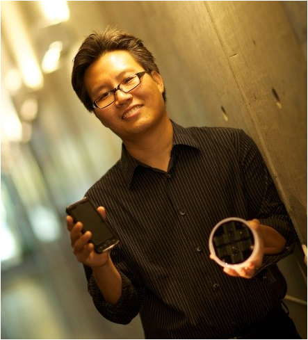 a man holding a phone and a petri dish