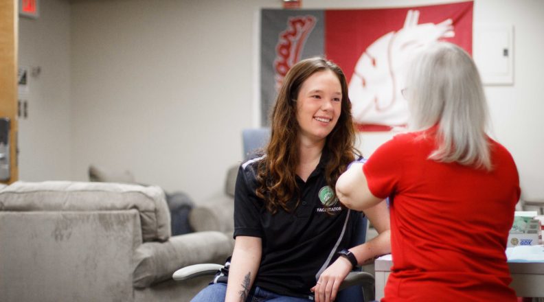 a girl getting a flu shot from a nurse in a room