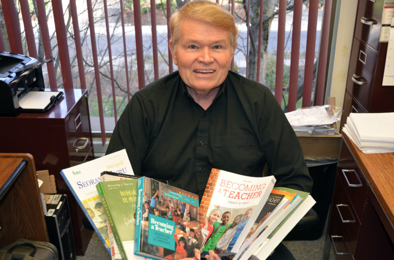 Forrest Parkay holding different editions of his book Becoming a Teacher.
