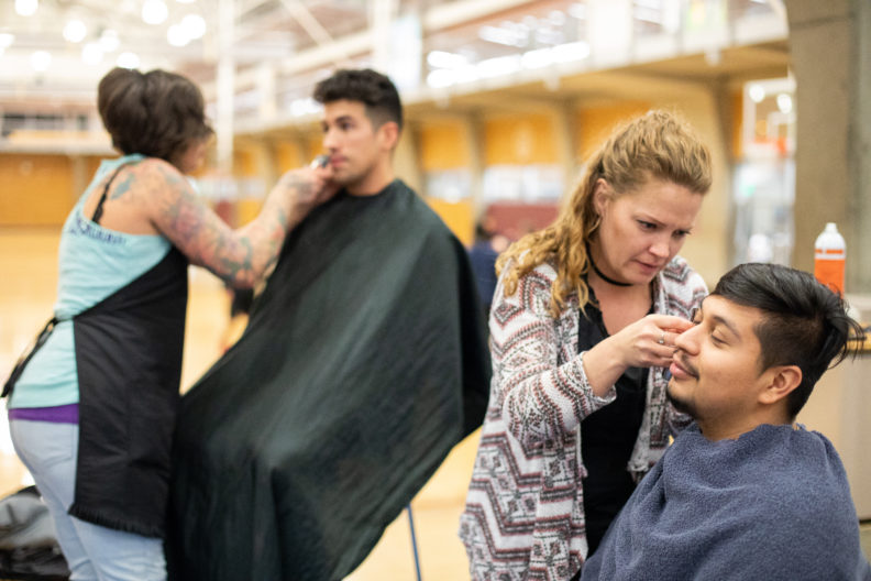 A photo of two hair stylists shaving two guys' beards
