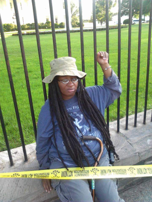 A photo of Anita Cameron, looking down and holding up her fist