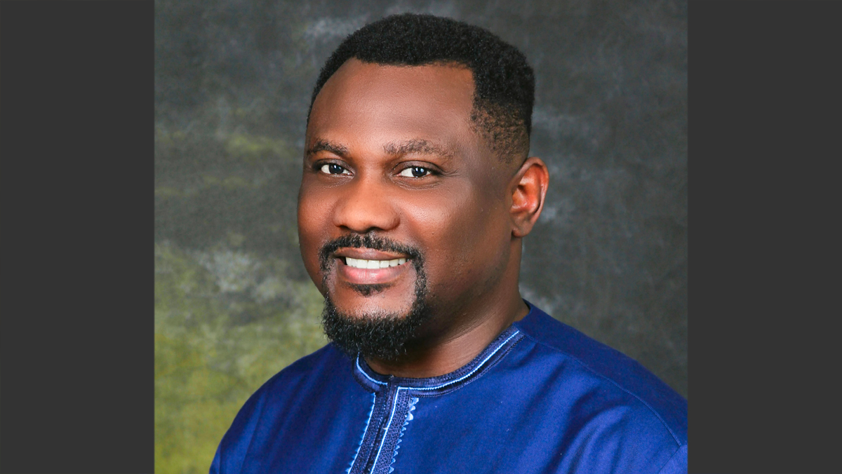 Professional headshot of Chris in a photo studio. He's wearing royal blue traditional top.
