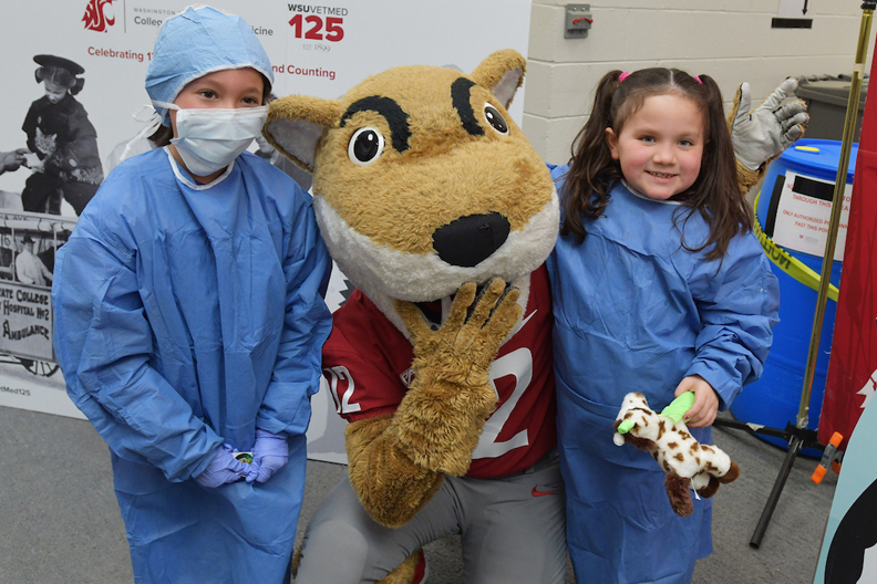 Two young girls wearing scrubs. Butch is between them.