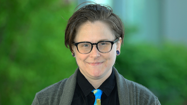 Kimber wearing a black shirt, colorful tie, and gray sweater.