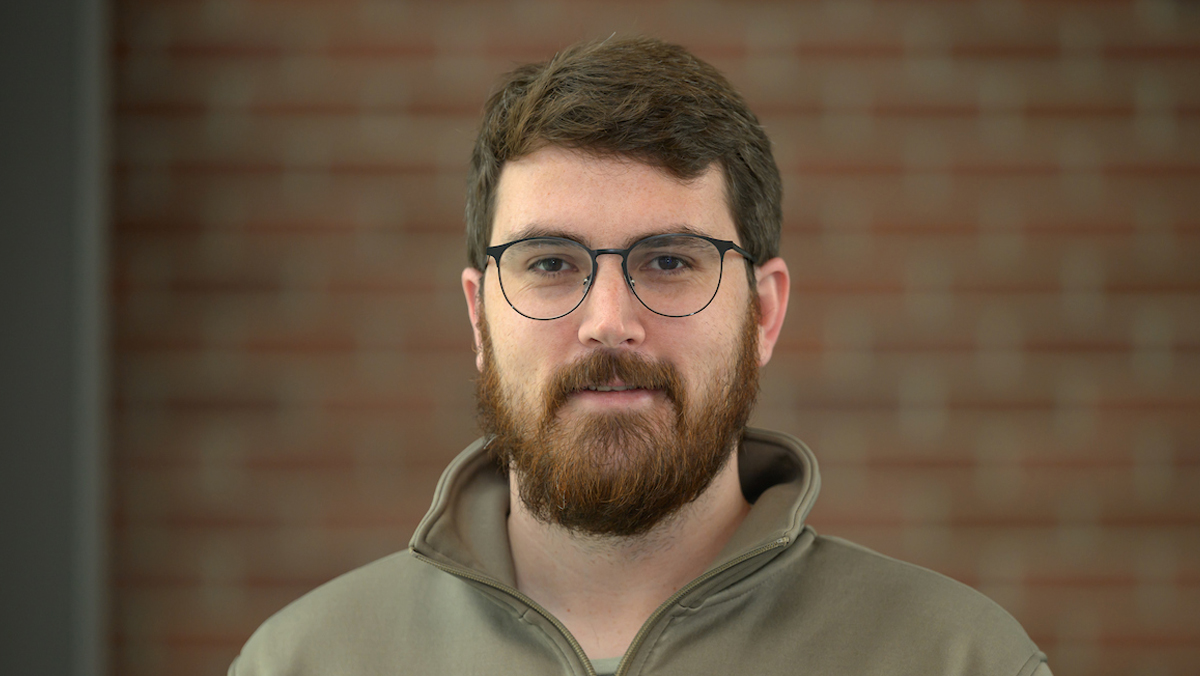 Hayden standing in front of a brick wall.