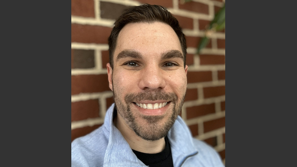 Headshot of Nick in front of a brick wall.