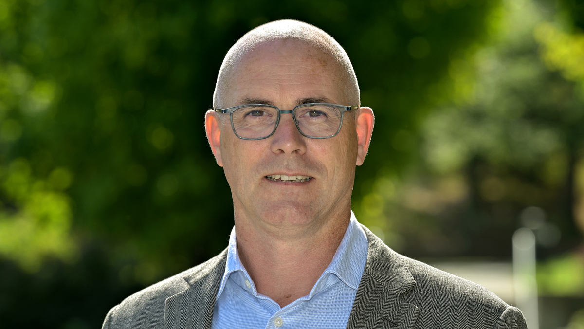 Dr. Arno Werners outside on a sunny day. He's wearing a grey jacket with a light blue button up shirt.