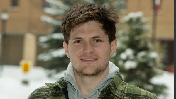 Brayden outside with snow on a tree in the background.