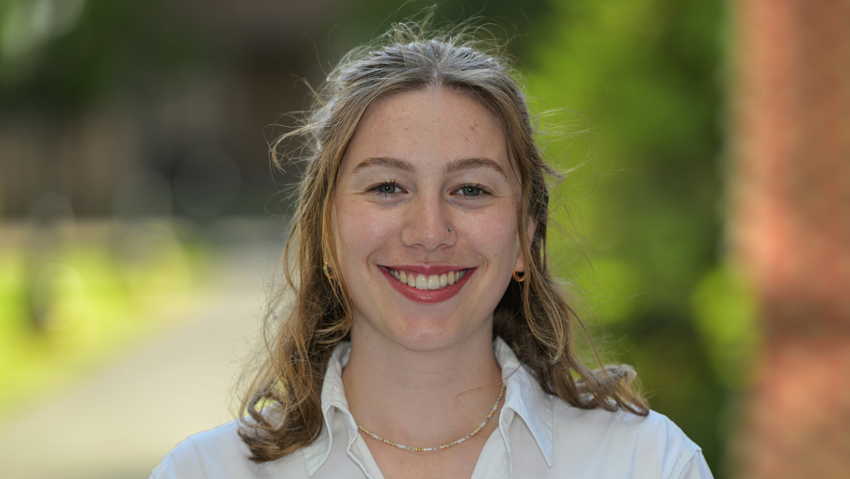 Sydni, wearing a white button up shirt, outside on a nice day.