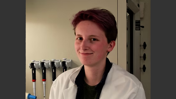 Danny, wearing a lab coat, in a lab.