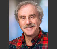 Dr. Steven wearing a red and blue plaid shirt.