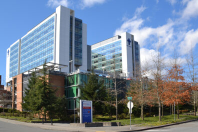 A tall medical building with large glass windows and surrounded by trees.