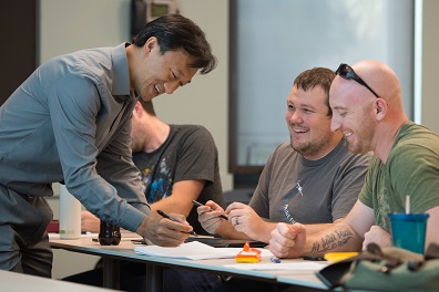 A WSU Everett professor smiling and leaning over to comment on student work.