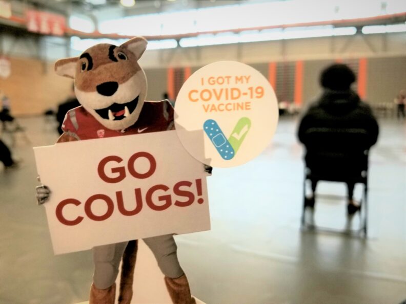 The WSU cougar mascot holding a sign that reads Go Cougs!