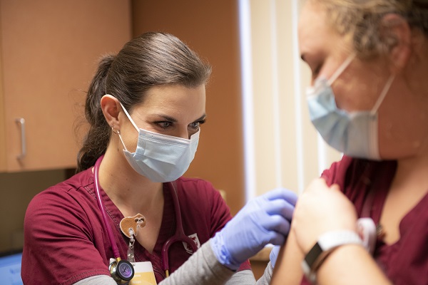 A medical worker in a face mask giving a shot.
