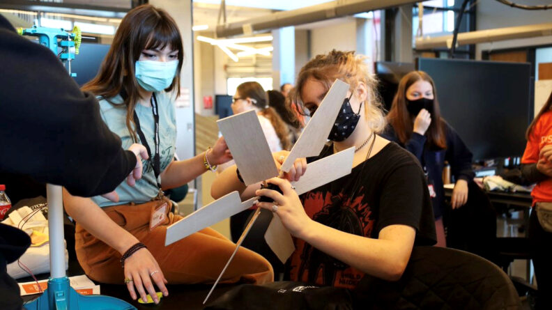 A group of students, some wearing face masks, working on a project.