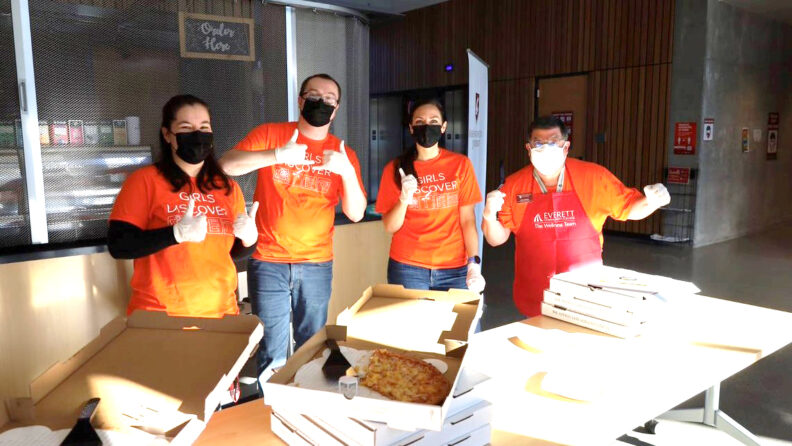 Four people in matching t-shirts with the text Girls Discover giving thumbs-up.
