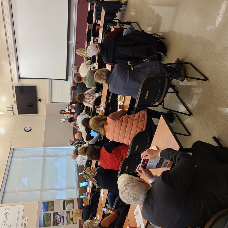 People sitting at rows of tables listening to a speaker.