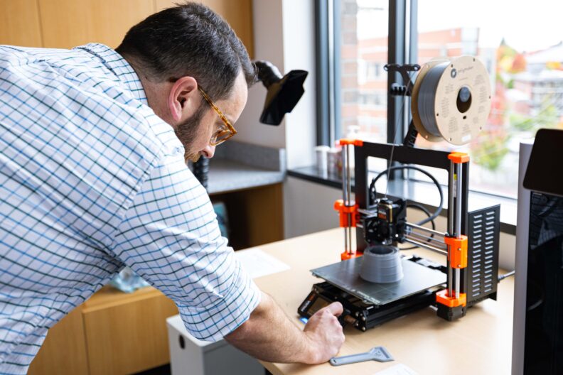 A person working with a small 3D printer.