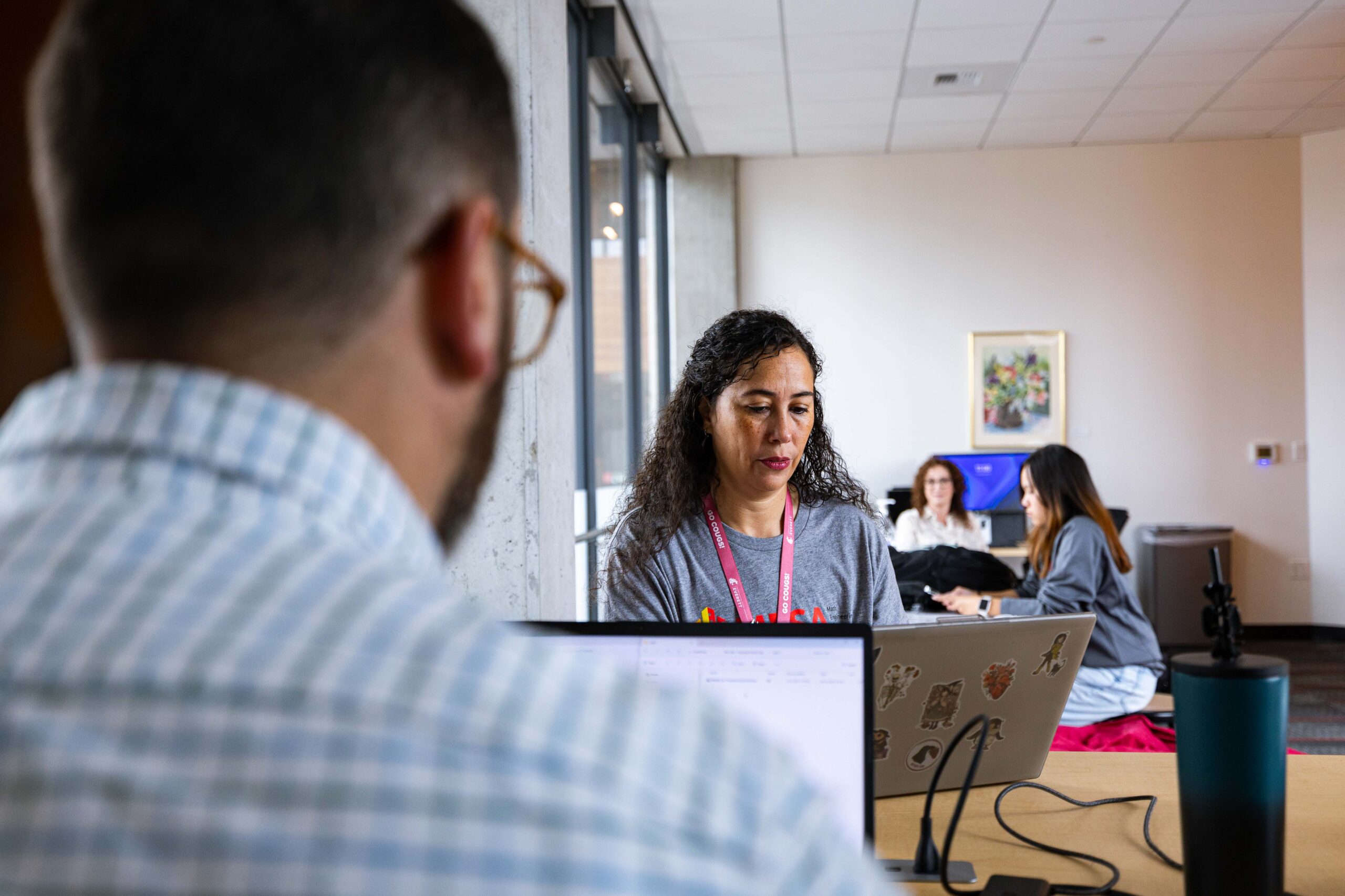 Two people working on laptops across from each other at a table.