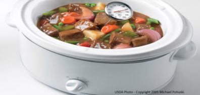 Slow cooker, with beef stew and a thermometer reading 140 degrees.
