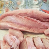 Tuna cut and prepared for canning with canning jars in background