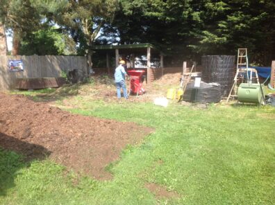 lawn with compost bins and a person working in the background