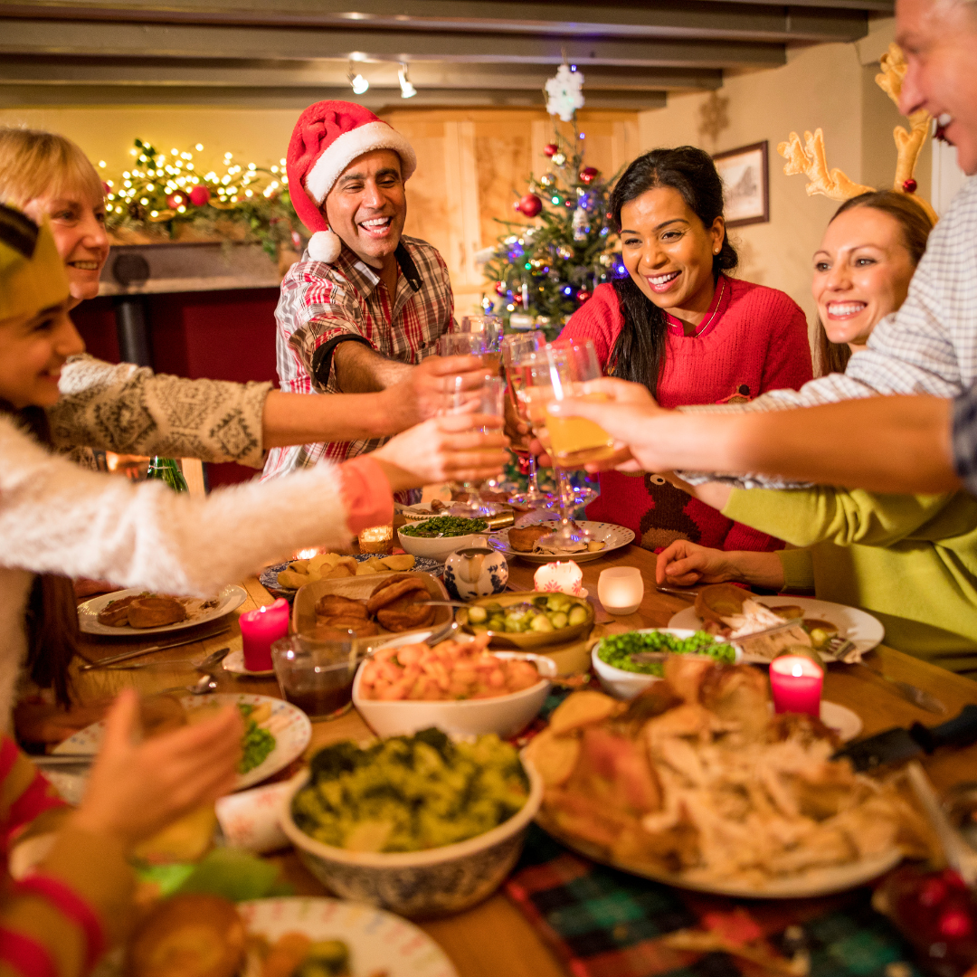 Family toasting with glasses over a large table of holiday food