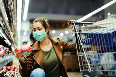 Young woman buying groceries while wearing face mask in the supermarket.