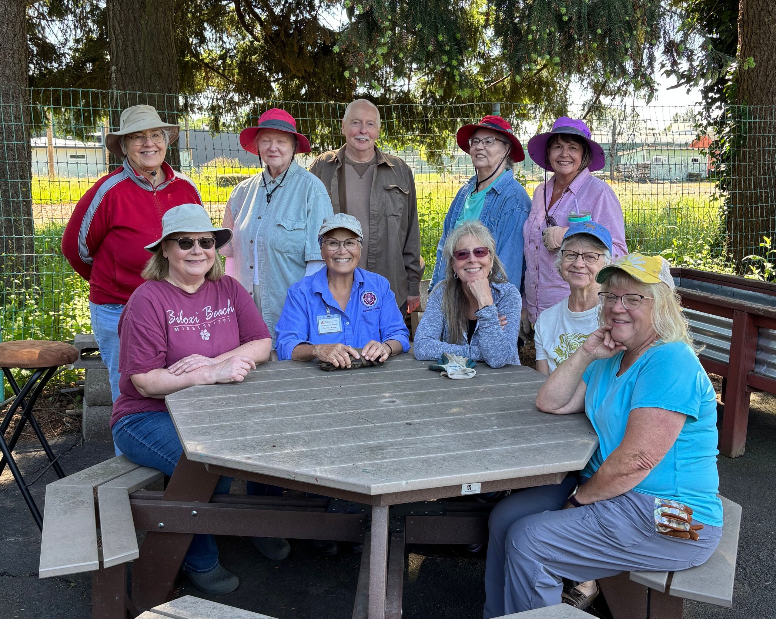A group of ten Extension Master Gardeners sitting and standing around picnic table.