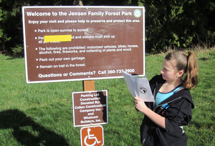 Child reading a park rules sign