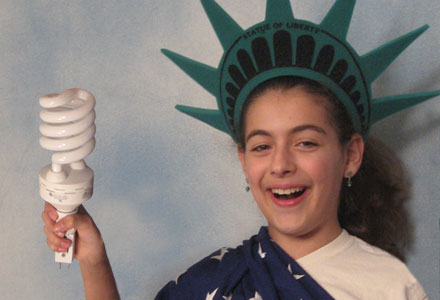 Child dressed as Statue of Liberty holding energy efficient light bulb