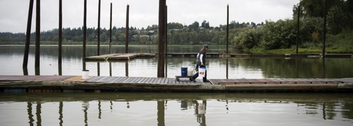 Person walking on a dock carrying buckets. 