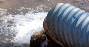 Large metal pipe with water discharging.