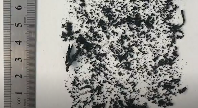Small black bits of tire particles with a scale to show how small they are. 