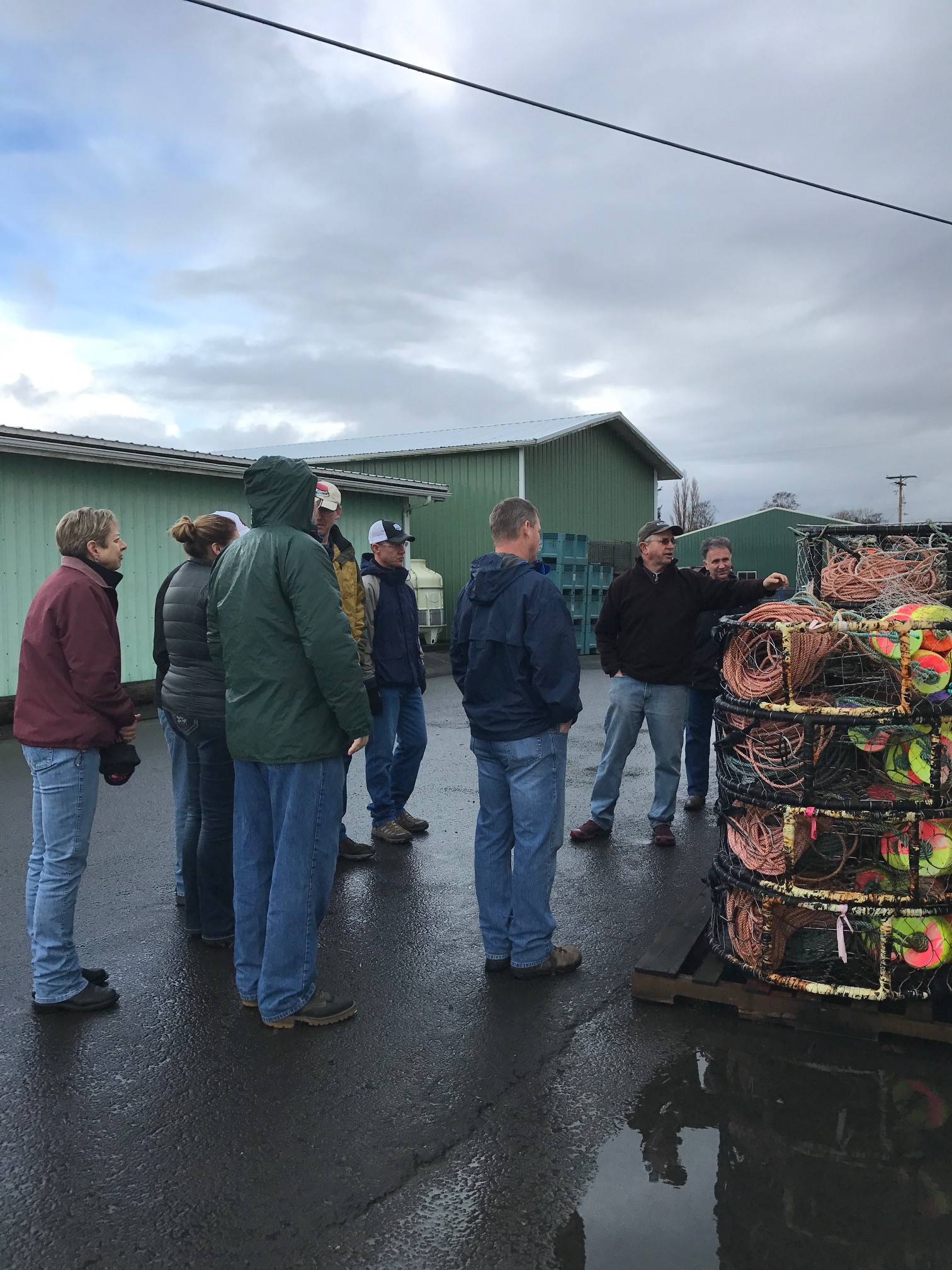 Tour group standing outside listening to a presentation in the rain.