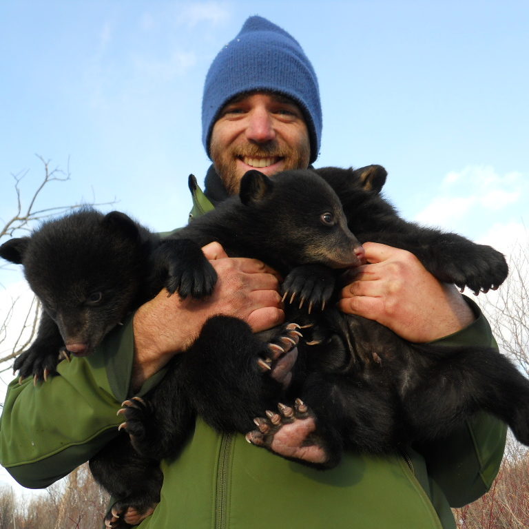 Michael holding three tiny bear cubs.